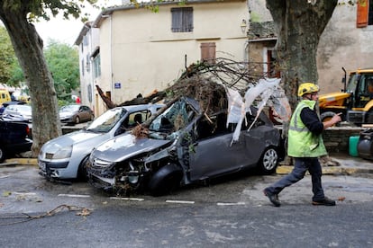 Un trabajador de emegencias pasa juntoa dos coches destrozados, en el distrito de Aude, en Villegailhenc (Francia).