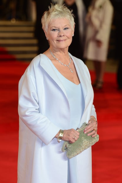 La actriz Judie Dench, muy elegante, con levita azul bebé y bolso de terciopelo y aplicaciones metálicas de estética vintage.