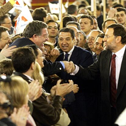 Mariano Rajoy y Eduardo Zaplana saludan a asistentes al mitin de anoche en Valencia.