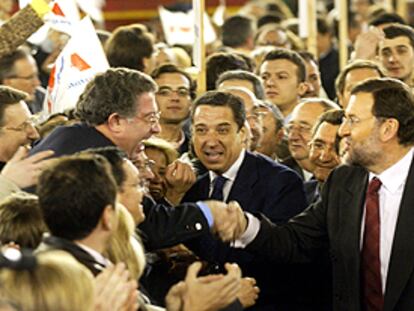 Mariano Rajoy y Eduardo Zaplana saludan a asistentes al mitin de anoche en Valencia.