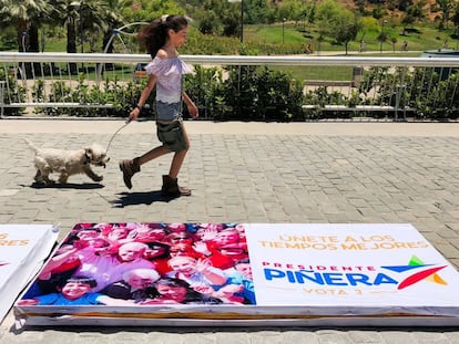 Una joven pasea en Santiago de Chile junto a un cartel electoral, el pasado domingo.