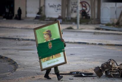 Un soldado traslada un retrato del dictador en la zona de Misrata controlada por las tropas gubernamentales.
