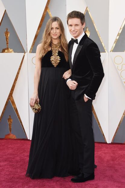 El actor inglés Eddie Redmayne, de 34 años, volvió a la alfombra roja del teatro Dolby de Los Ángeles con una gran sonrisa, no solo porque próximamente será padre, sino también porque volvía a estar nominado a mejor actor gracias a su trabajo en ‘La chica danesa’. El ganador del Oscar como Stephen Hawking en ‘La teoría del todo’ llegó acompañado por su esposa Hannah Bagshawe. El intérprete escogió un traje negro de terciopelo y pajarita de la firma británica Alexander McQueen.
Redmayne se casó en diciembre de 2014 con Hannah Bagshawe, en una ceremonia en Babington House en Somerset, lugar que fue escenario de otras bodas de ‘celebrities’ como Zoe Ball y Fatboy Slim, James Corden y Julia Carey, entre otros.