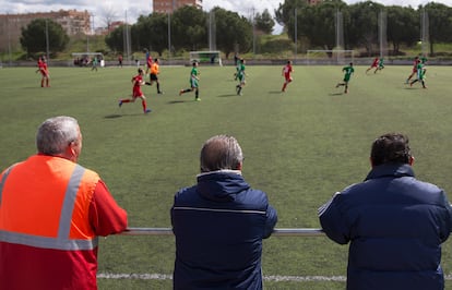 Varios padres observan desde la banda un partido infantil, en Madrid.