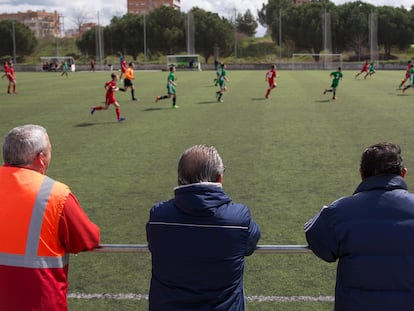 Varios padres observan desde la banda un partido infantil, en un campo de Parla (Madrid) a finales de julio.