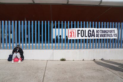 Una mujer al lado de un cartel de la huelga de transporte en la estación de autobuses de Santiago.