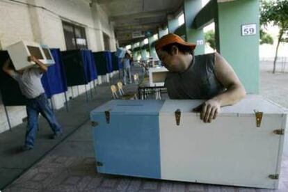 Varios operarios llevan las urnas al Estadio Nacional, convertido en uno de los colegios electorales de Santiago.
