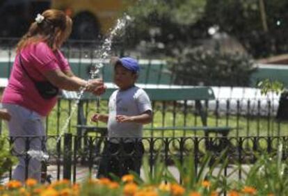 Unos argentinos se refrescan en aspersores de agua este jueves 16 de enero de 2014, en el centro de Buenos Aires (Argentina).