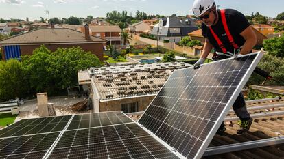 Un operario de Holaluz instala un panel en el tejado de una casa en Madrid, en 2022.
