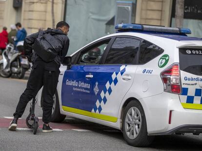 Un agent de la Guàrdia Urbana amonesta un home amb patinet. 