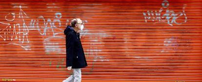 Un hombre con mascarilla sanitaria pasa frente a una oficina pública de empleo cerrada en Oviedo.