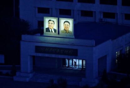 Retratos dos últimos líderes norte-coreanos Kim Il Sung e Kim Jong Il na fachada de um edifício na Universidade Tecnológica Kim Chaek, antes do amanhecer, em Pyongyang.