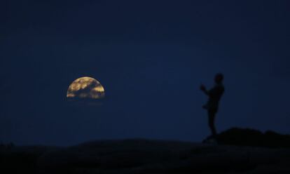 Una mujer observa la luna cerca de la playa Bondi en Sídney (Australia).