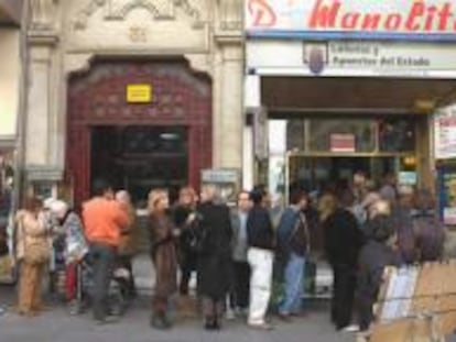 Un grupo de personas esperan su turno para comprar lotería de Navidad de Doña Manolita, en Madrid.