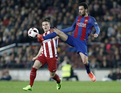 Sergio Busquets intenta controlar el balón ante el delantero francés del Atlético de Madrid, Kevin Gameiro.