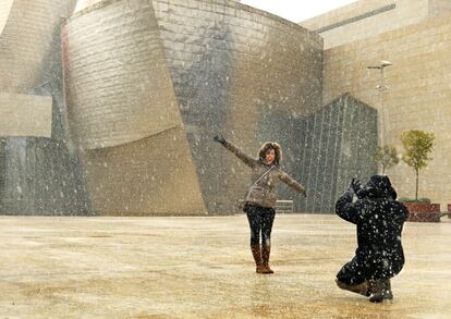 Una pareja se fotografía ante el Museo Guggenheim de Bilbao, donde la nieve ha empezado a caer de forma débil