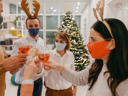 Un grupo de personas con mascarilla durante un brindis por Navidad. GETTY IMAGES