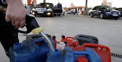 Un hombre llena con combustible en una gasolinera varios bidones.