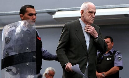 El exdictador Reynaldo Bignone, escoltado por un policía durante un juicio por delitos de lesa humanidad en 2010.