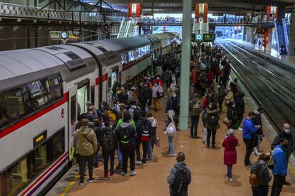 Decenas de personas esperan en un anden de Cercanías de la estación de Atocha este lunes, primer día laborable con las nuevas restricciones establecidas en Madrid capital y otros nueve municipios para frenar la expansión del coronavirus.