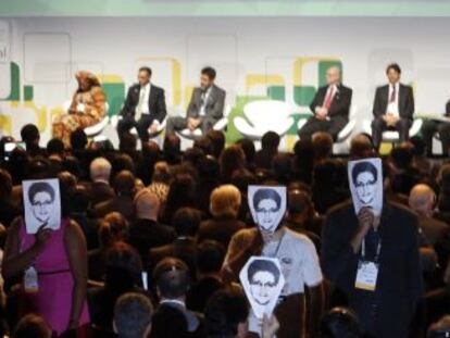 Asistentes a la cumbre de Internet de Sao Paulo muestran fotos de Edward Snowden durante la intervenci&oacute;n de Dilma Rousseff.