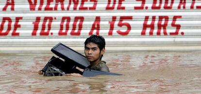 Un joven con un ordenador en una calle inundada de Acapulco.