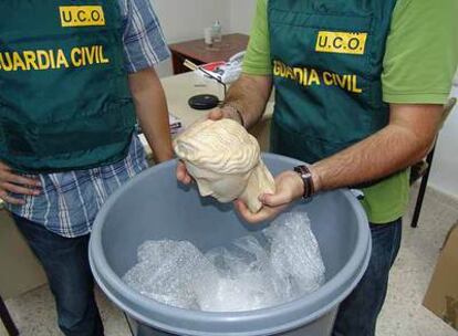 Dos agentes de la Guardia Civil muestran una de las esculturas halladas en un cubo de basura.