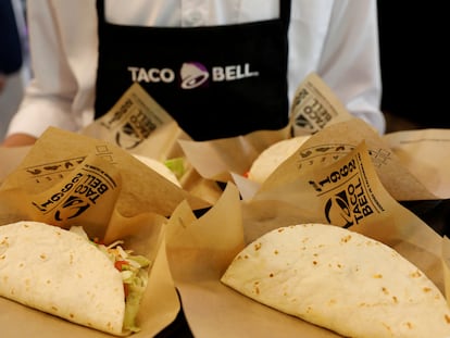 Un empleado de Taco Bell muestra una bandeja llena de tacos.
