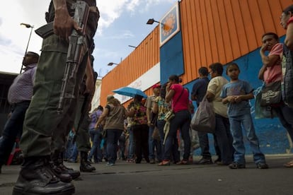 People stand in line outside a supermarket in Venezuela.