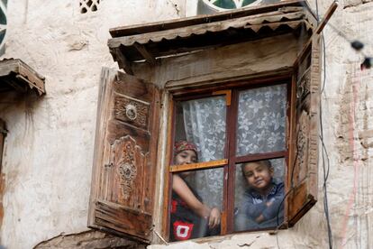 Dos niños miran a través de la ventana de su casa en el casco viejo de Saná, capital de Yemen, el 8 de agosto de 2018. La infancia es, cada vez más, blanco de ataques deliberados en contextos de conflicto, desde secuestros, reclutamiento o agresiones sexuales hasta asesinatos.