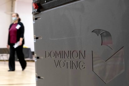 A worker passes a Dominion Voting ballot scanner while setting up a polling location at an elementary school in Gwinnett County, Ga., outside of Atlanta, on Jan. 4, 2021