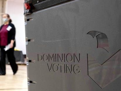 A worker passes a Dominion Voting ballot scanner while setting up a polling location at an elementary school in Gwinnett County, Georgia, on January 4, 2021.