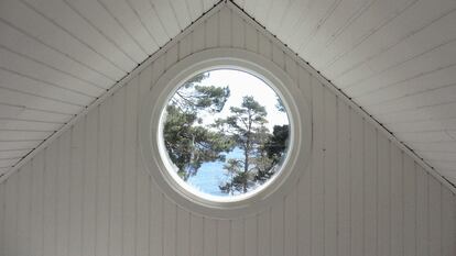 Un ático con una ventana redonda con vistas al mar.