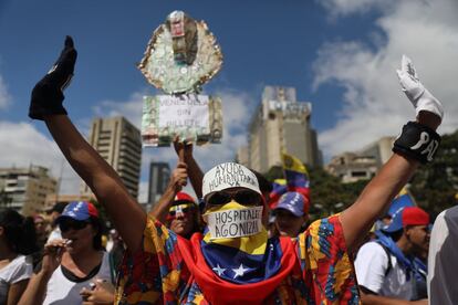 Decenas de miles de venezolanos se movilizaron este sábado en diferentes cuarteles de las Fuerzas Armadas para exigir a los militares dar apoyo a la entrada de la ayuda humanitaria que se almacena en distintos puntos fronterizos. En la imagen, un hombre porta los eslóganes "Ayuda humanitaria ya" y "hospitales agonizan", durante una protesta en Caracas.