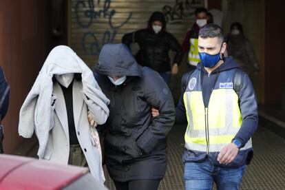 Un agente de la Policía Nacional acompaña a dos de los detenidos en la operación de este lunes en el Ayuntamiento de Cornellà.