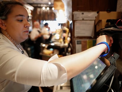 En la imagen, una camarera del Bar Gandarias de San Sebastián fichando este jueves con la pulsera digital para el control de horario telemático. EFE/Juan Herrero.