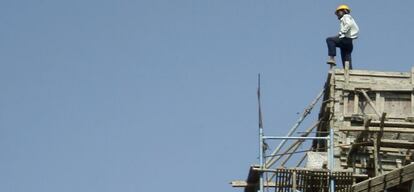 Un trabajador en lo alto de un edificio en construcción en la India.