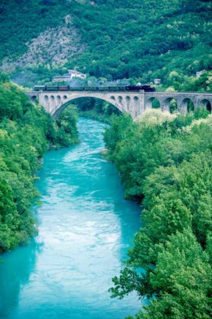 El antiguo tren a vapor de la línea de ferrocarril de Bohinj en un puente sobre río de Soca (Eslovenia).