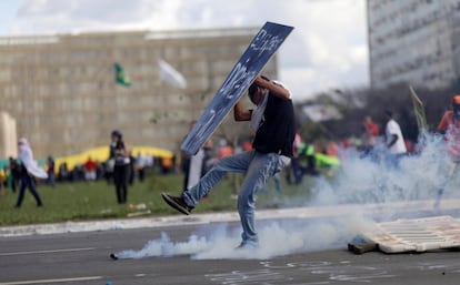 Un manifestante con una pancarta se enfrenta a los antidisturbios.