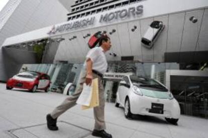 Un hombre camina cerca de dos coches eléctricos i MiEV de la empresa Mitsubishi Motors Corps. en un concesionario de esta firma en Tokio. EFE/Archivo