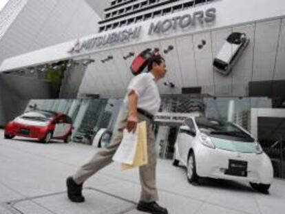 Un hombre camina cerca de dos coches eléctricos i MiEV de la empresa Mitsubishi Motors Corps. en un concesionario de esta firma en Tokio. EFE/Archivo