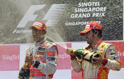 Lewis Hamilton, a la izquierda, es rociado con champán por Fernando Alonso en el podio del Gran Premio de Singapur, el 27 de septiembre de 2009, tras haber quedado primero y tercero respectivamente.