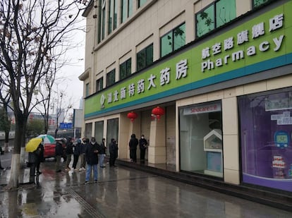 People wait outside a pharmacy in Wuhan.