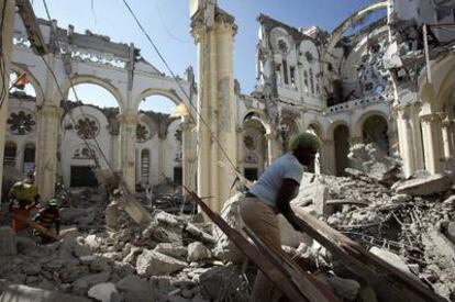 Varias personas buscan entre los escombros de la catedral de Puerto Príncipe material para reconstruir casas.