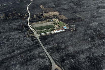 Fotografía tomada con un dron de una vivienda rodeada por la superficie calcinada en el pueblo de San Cibrao (Oímbra), este viernes.