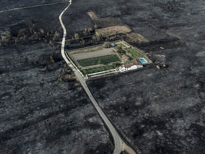 Fotografía tomada con un dron de una vivienda rodeada por la superficie calcinada en el pueblo de San Cibrao (Oímbra), este viernes.