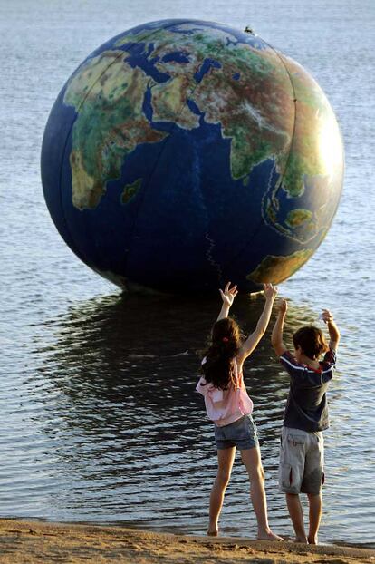 Dos niños juegan ante un globo terráqueo inflable en Porto Alegre.