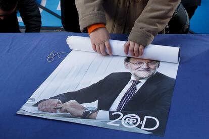 Un partidario del Partido Popular enrolla un cartel de Mariano Rajoy en el último día de la campaña, en el centro de Madrid.