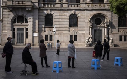 Además de por el abundante número de personas con máscaras, la huella que ha dejado la epidemia se deja ver de otras formas. En la foto, un grupo de personas mayores hacen cola enfrente de un banco manteniendo la distancia de seguridad.