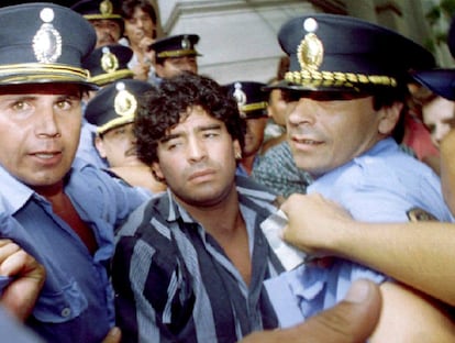 Maradona es escoltado por la policía al salir del juzgado tras responder a los cargos por lesión a periodistas en el exterior de su casa, en Mercedes (Argentina), en 1994.